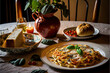 pasta, bread and other italian food on a table with a plant on the table