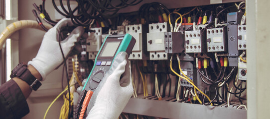 Wall Mural - Electrician engineer tests electrical installations and wires on relay protection system.