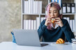 © crizzystudio - Asian businesswoman sitting and eating bread watching cell phones and reading break books Relax in the office to work happily and deliciously.