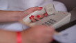 © H_Ko - Woman dialing phone number on white landline phone in hotel