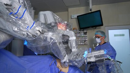 Wall Mural - The patient is operated by the futuristic robotic equipment. Male doctor watches the operation carefully at the screen.