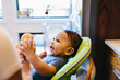 © Cavan Images - Close-up of happy boy sitting on high chair at home