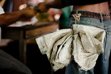 A Plastic Bag Tied To The Belt Of A Man Who's Getting Paid After A Day Of Work At A Coffee Plant In Chiapas, Mexico.