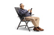 © Ljupco Smokovski - Casual mature man sitting at a foldable chair and using a smartphone