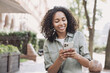 © kite_rin - Young beautiful woman using smartphone in a city. Smiling student girl texting on mobile phone outdoor. Modern lifestyle, connection, casual business concept