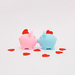 Pink and blue piggy banks in love with red hearts. Concept of love and saving.