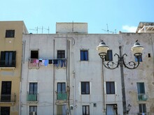 Trapani White Building Facade View With Hanging Laundry And Lamp Post In Sicily, Italy
