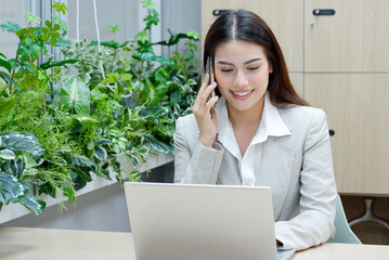 Wall Mural - female employee sitting at the table using a smartphone for work.