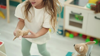 Poster - Adorable blonde girl student listening to music reading book at kindergarten