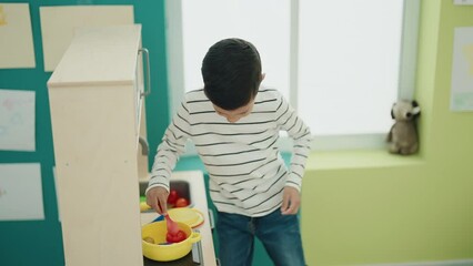 Canvas Print - Adorable hispanic boy playing with play kitchen standing at kindergarten