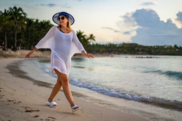 Wall Mural - Woman walking on sunny, tropical beach at daybreak
