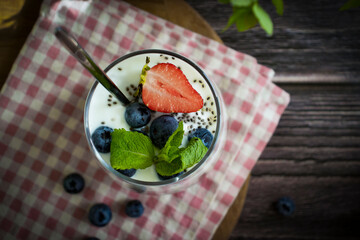 Wall Mural - Yogurt, chia seeds, blueberries, strawberries, raspberries, mint, kiwi on a dark background