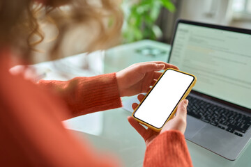 Over shoulder view of woman holding mobile phone with white blank mock up cellular screen apps working or elearning using cell phone. Cellphone display mock up for advertising concept.
