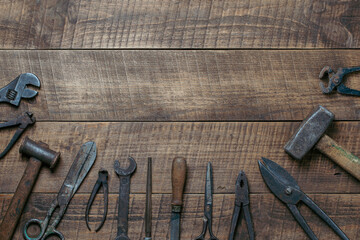 Vintage tools displayed on a background of wooden board, closeup, top view, copy space. Dirty set old working tools