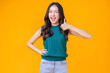 © whyframeshot - casual happiness asian female woman smiling cheerful in green tshirt blue jean relax peaceful positive thinking carefree lifestyle standing hand gesture face expression with yellow color background