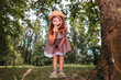 © _KUBE_ - Cute little girl looks through a magnifying glass at the camera. Bottom view. Park in the background. The concept of scouting and children's education