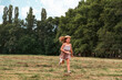 © _KUBE_ - Summer holidays. Happy little girl in a cute hat and dress runs at the the park. Tilted horizon. Copy space. The concept of childhood and Children's Day
