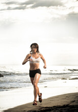 A Young Woman Endurance Athlete  Runs On The Beach In Santa Barbara, California.