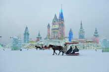 A Horse Drawn Carriage Passes A Brightly Lit Ice Castle In Harbin.