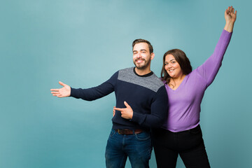 Wall Mural - Smiling young couple showing a new product or ad