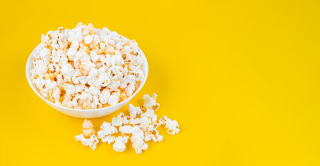 scattered tasty cheese popcorn in bowl isolated on yellow background. wallpaper, banner, header with