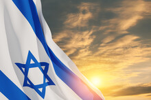 Israel Flag With A Star Of David Over Cloudy Sky Background On Sunset. Patriotic Concept About Israel With National State Symbols. Banner With Place For Text.