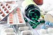 Nahaufnahme verschiedener Medikamente in teils geöffneten Packungen, Glasflasche und Blisterverpackung