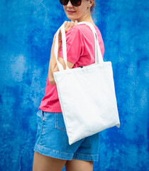 Wall Mural - Female model wearing pink blank t-shirt on the background of an blue wall.