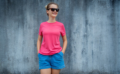 Wall Mural - Female model wearing pink blank t-shirt on the background of an gray scratched wall.