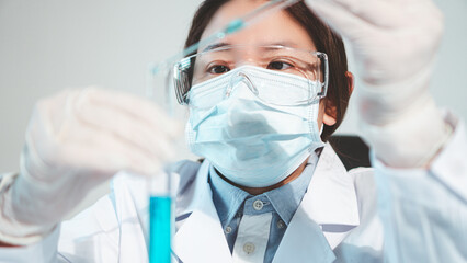 Asian woman Scientist experimental in laboratory with test tube and beaker for medical research