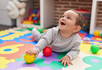 Canvas Print - Adorable hispanic baby playing with balls lying on floor at kindergarten