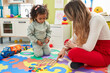 © Krakenimages.com - Teacher and toddler playing with maths puzzle game sitting on floor at kindergarten