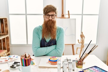 Wall Mural - Redhead man with long beard painting clay bowl at art studio skeptic and nervous, disapproving expression on face with crossed arms. negative person.