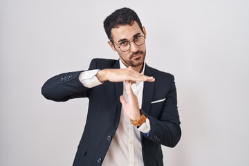 Sticker - Handsome business hispanic man standing over white background doing time out gesture with hands, frustrated and serious face