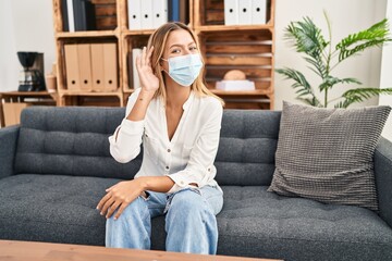 Canvas Print - Young blonde woman treating covid fear at therapy smiling with hand over ear listening and hearing to rumor or gossip. deafness concept.