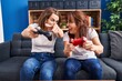 © Krakenimages.com - Two women mother and daughter playing video game sitting on sofa at home