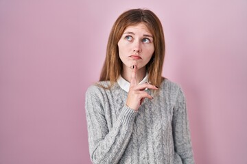 Sticker - Beautiful woman standing over pink background thinking concentrated about doubt with finger on chin and looking up wondering