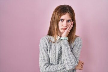 Wall Mural - Beautiful woman standing over pink background thinking looking tired and bored with depression problems with crossed arms.