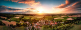 Fototapeta  - Aerial panorama of a village surrounded by fields at sunrise, with beautiful colorful sky and warm light