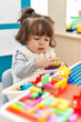© Krakenimages.com - Adorable hispanic toddler playing with construction blocks sitting on table at kindergarten