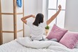 © Krakenimages.com - Young hispanic woman waking up sitting on bed at bedroom