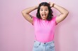 © Krakenimages.com - Young hispanic woman standing over pink background crazy and scared with hands on head, afraid and surprised of shock with open mouth