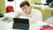 © Krakenimages.com - Adorable hispanic boy student sitting on table doing homework at classroom