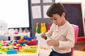 Poster - Adorable hispanic boy playing with construction blocks sitting on table at kindergarten