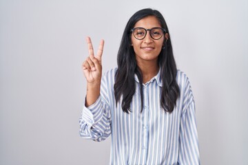 Sticker - Young hispanic woman wearing glasses showing and pointing up with fingers number two while smiling confident and happy.