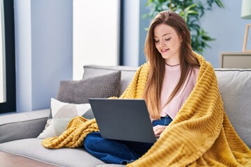 Poster - Young caucasian woman using laptop sitting on sofa at home