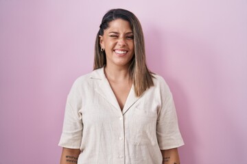 Sticker - Blonde woman standing over pink background winking looking at the camera with sexy expression, cheerful and happy face.