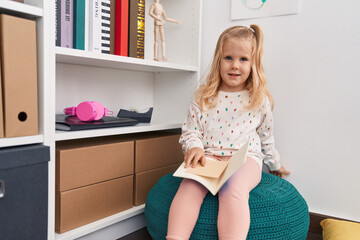 Sticker - Adorable blonde girl holding book sitting at library school