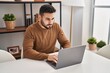 © Krakenimages.com - Young hispanic man using laptop sitting on table at home