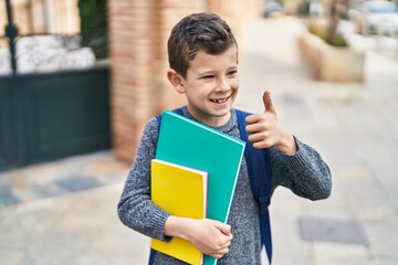 Poster - Blond child student holding books doing ok gesture at street